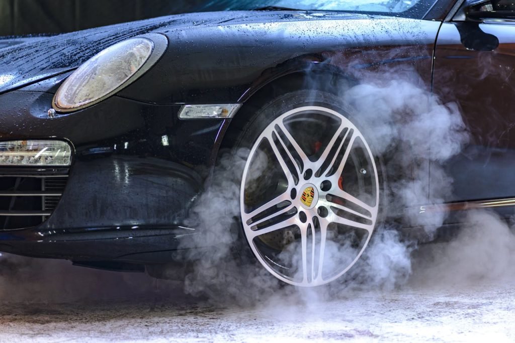Close-up of a luxury car wheel with steam and water droplets, showcasing power and style.
